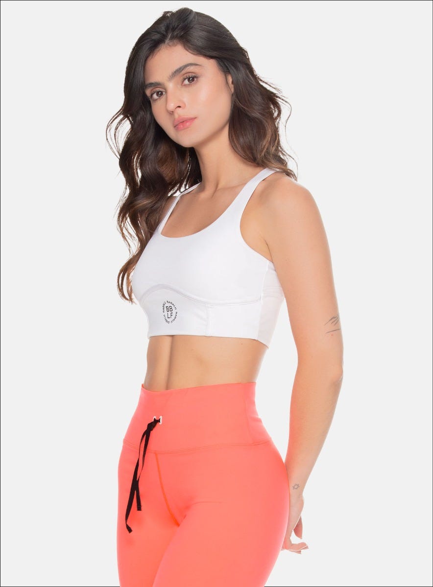 TOP DEPORTIVO CON SESGOS AEREOS DECORATIVOS, FORRO INTERNO, ELÁSTICO EXPUESTO EN LA ESPALDA Y APLQUE DECORATIVO EN EL FRENTE.