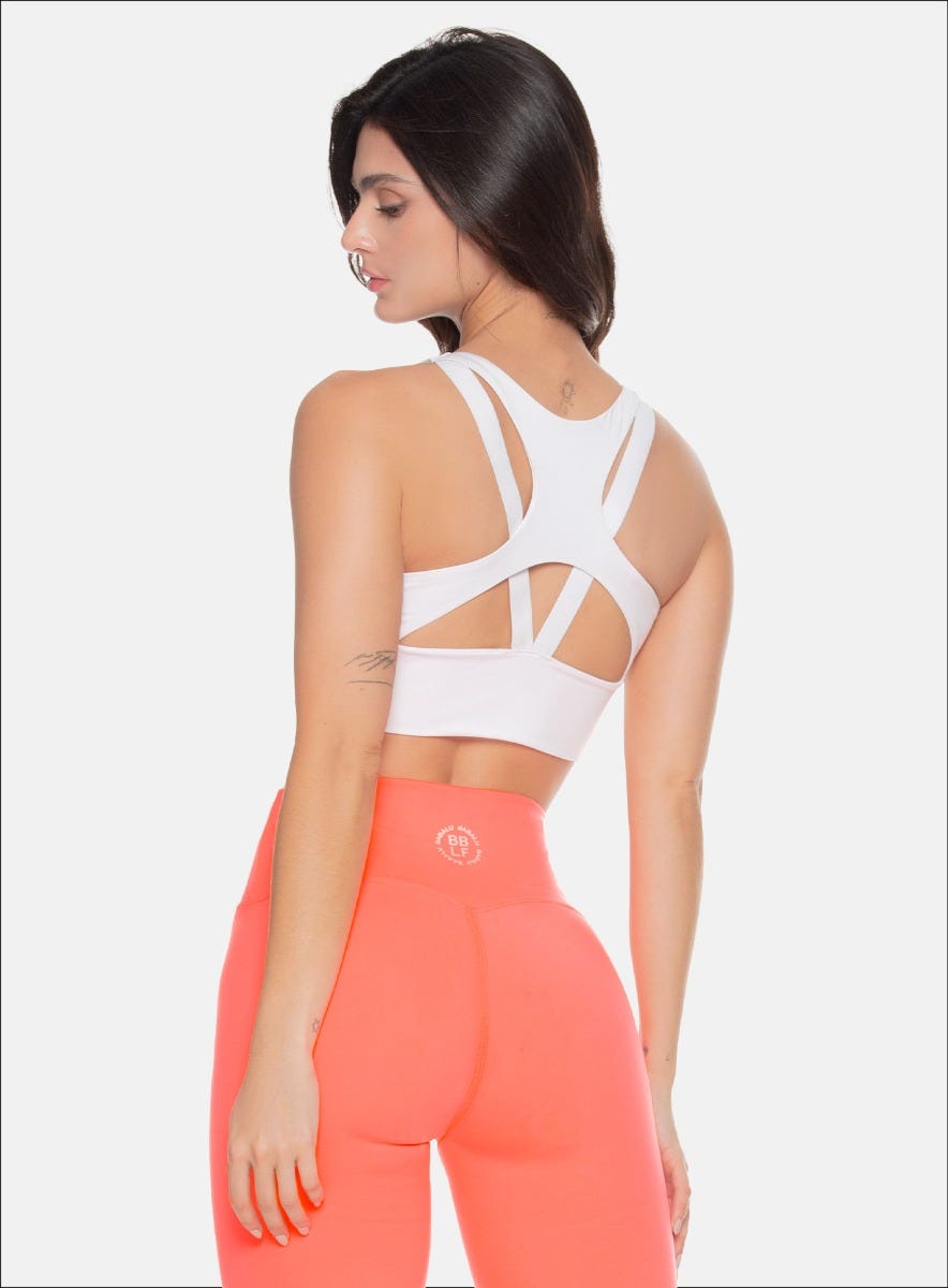 TOP DEPORTIVO CON SESGOS AEREOS DECORATIVOS, FORRO INTERNO, ELÁSTICO EXPUESTO EN LA ESPALDA Y APLQUE DECORATIVO EN EL FRENTE.